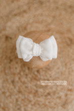 White bow on a wooden block with a blurred brown background