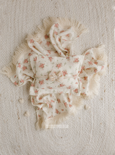 Floral baby outfit with matching headband on a textured beige background