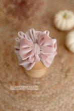 Pink velvet turban hat with bow on a posing ball with a blurred background, pumpkins.