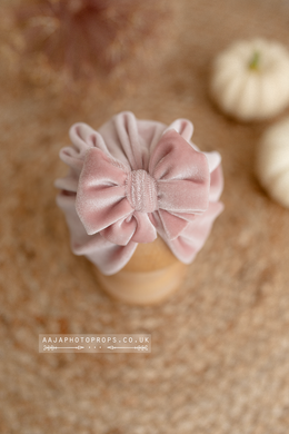 Pink velvet turban hat with bow on a posing ball with a blurred background, pumpkins.
