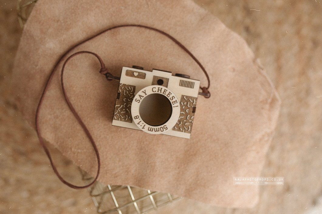 Camera-shaped object with 'Say Cheese' text on a textured surface