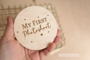 Wooden disc with 'My First Photoshoot' engraving held in a hand.
